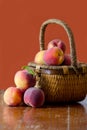 Peaches and basket on rust colored background