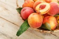 Peaches in a basket on a wooden background with a slice of sliced juicy peach with a stone. Royalty Free Stock Photo