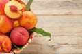 Peaches in a basket on a wooden background with a slice of sliced juicy peach with a stone. Royalty Free Stock Photo