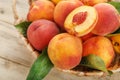 Peaches in a basket on a wooden background with a slice of sliced juicy peach with a stone Royalty Free Stock Photo