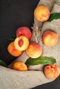 Peaches on a black background with burlap fabric and green leaves. Sweet and juicy peach slices with a stone Royalty Free Stock Photo