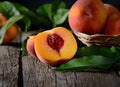 Peaches on a branch with leaves in a wooden bowl on dark wooden background