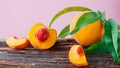 Peaches with leaves on wooden board. Peach in halves with bone, chopped pieces wedges peach halves. Ripe juicy peaches. Fresh