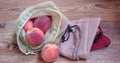 Peaches in reusable eco bags for fruits and vegetables on wooden surface
