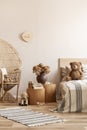 Peacock chair with pillow and teddy bear next to two nightstands with books and vase with flowers and single bed with toy on it Royalty Free Stock Photo