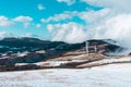 Peak of the mountain with electric turbine blades view on a snowy hill mountain