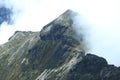 The peak of a mountain without much green and covered in fog