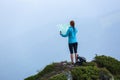 On the peak of the mountain the touris girl with the map and compass is searching for the way to dream. The horizon in the fog. Royalty Free Stock Photo