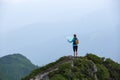 On the peak of the mountain the touris girl with the map and compass is searching for the way to dream. The horizon in the fog. Royalty Free Stock Photo