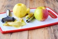Pealed apples wih the core taken away with special knives on a white cutting board on a wooden background. Step by step