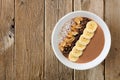 Peanut-butter, banana, chocolate smoothie bowl on rustic wood Royalty Free Stock Photo