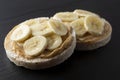 Peanut butter and banana on rice cakes, healthy, dietary food. Black background Royalty Free Stock Photo