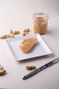 Peanut butter bread sandwich on white square shaped plate peanuts nut table knife wooden background Royalty Free Stock Photo