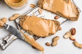 Peanut butter in a glass jar, peanuts, kitchen knife and peanut butter sandwiches on white background. Top view Royalty Free Stock Photo