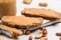 Peanut butter in a glass jar, peanuts, kitchen knife and peanut butter sandwiches on white background. Vegan food Royalty Free Stock Photo