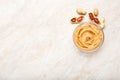 Peanut butter in a glass plate with peanuts in shell and peeled peanuts. Creamy peanut paste flat lay with place for text on white Royalty Free Stock Photo