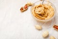 Peanut butter in glass plate with peanuts in shell, peeled peanuts, spoon with peanut butter. Creamy peanut paste flat lay with Royalty Free Stock Photo