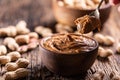 Peanut butter on spoon bowl and peanuts on wooden table