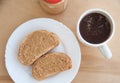 Peanut butter toasts on a white plate, a cup of coffee and jar on the wooden table. Top view Royalty Free Stock Photo