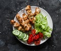 Peanut butter, yogurt and soy sauce chicken satay skewers with fresh vegetables salad on a dark background, top view Royalty Free Stock Photo