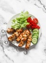 Peanut butter, yogurt and soy sauce chicken satay skewers with fresh vegetables salad on a light background, top view. Delicious Royalty Free Stock Photo