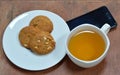 Peanut cookie and cup of tea with black cell phone