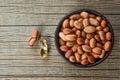 Peanut in nutshell in brown bowl on wooden background. Composition of peanuts Royalty Free Stock Photo