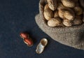 Peanut in nutshell in burlap sack or sackcloth on wooden background. Composition of peanuts Royalty Free Stock Photo