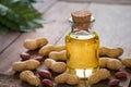 Peanut oil in glass bottle and peanuts on wooden table Royalty Free Stock Photo