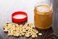 Peanut paste in open plastic jar, red cap, fried peanuts Royalty Free Stock Photo