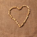 Peanuts . arranged to form a heart. Rustic background of raw yuta canvas. Delicious food. Royalty Free Stock Photo