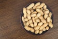 Peanuts in a ceramic bowl on a wooden background