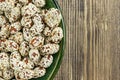 Peanuts covered with sesame seeds in a green plate on a brown wooden surface Royalty Free Stock Photo