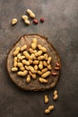 Peanuts on a cutting board stump, brown dark background. Top view, flat lay Royalty Free Stock Photo