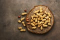 Peanuts on a cutting board stump, brown dark background. Top view, flat lay Royalty Free Stock Photo