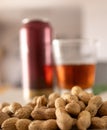 Peanuts in the foreground next to a fresh beer, ideal for a summer aperitif.Out-of-focus background Royalty Free Stock Photo