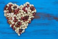 Peanuts nuts in heart shape on blue rustic wood background.