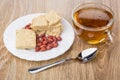 Peanuts and pieces of peanut halva, tea and teaspoon