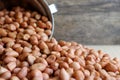 Peanuts in stainless cup on wooden background.