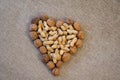 Peanuts and walnuts arranged to form a heart. Rustic background of raw yuta canvas - delicious food Royalty Free Stock Photo