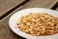 Peanuts in white plate on a wood background