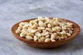 Peanuts in wooden plate isolated over white textured background, top view, close-up. Royalty Free Stock Photo