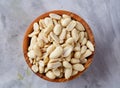 Peanuts in wooden plate over white textured background, top view, close-up. Royalty Free Stock Photo