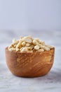 Peanuts in wooden plate over white textured background, top view, close-up. Royalty Free Stock Photo