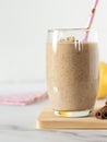 Pear banana cinnamon smoothie in glass with eco-friendly straw on table with white background