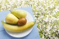 Pear, banana and kiwi fruit on wooden blue table and on natural flowers background. Fresh organic fruits. Top view. Copy space Royalty Free Stock Photo