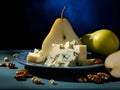 Pear and blue cheese plate. Fresh pear slices served with blue cheese and walnuts on a dark ceramic plate on a dark turquoise