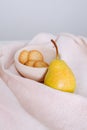Pear and cookies on a bowl on a crumpled tablecloth with checkered texture