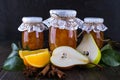 Pear and orange jam in glass jars with ripe pears, cinnamon sticks, anise stars and green leaves on the table. Royalty Free Stock Photo