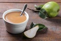 Pear puree in a white bowl next to fresh pears on a wooden brown table Royalty Free Stock Photo